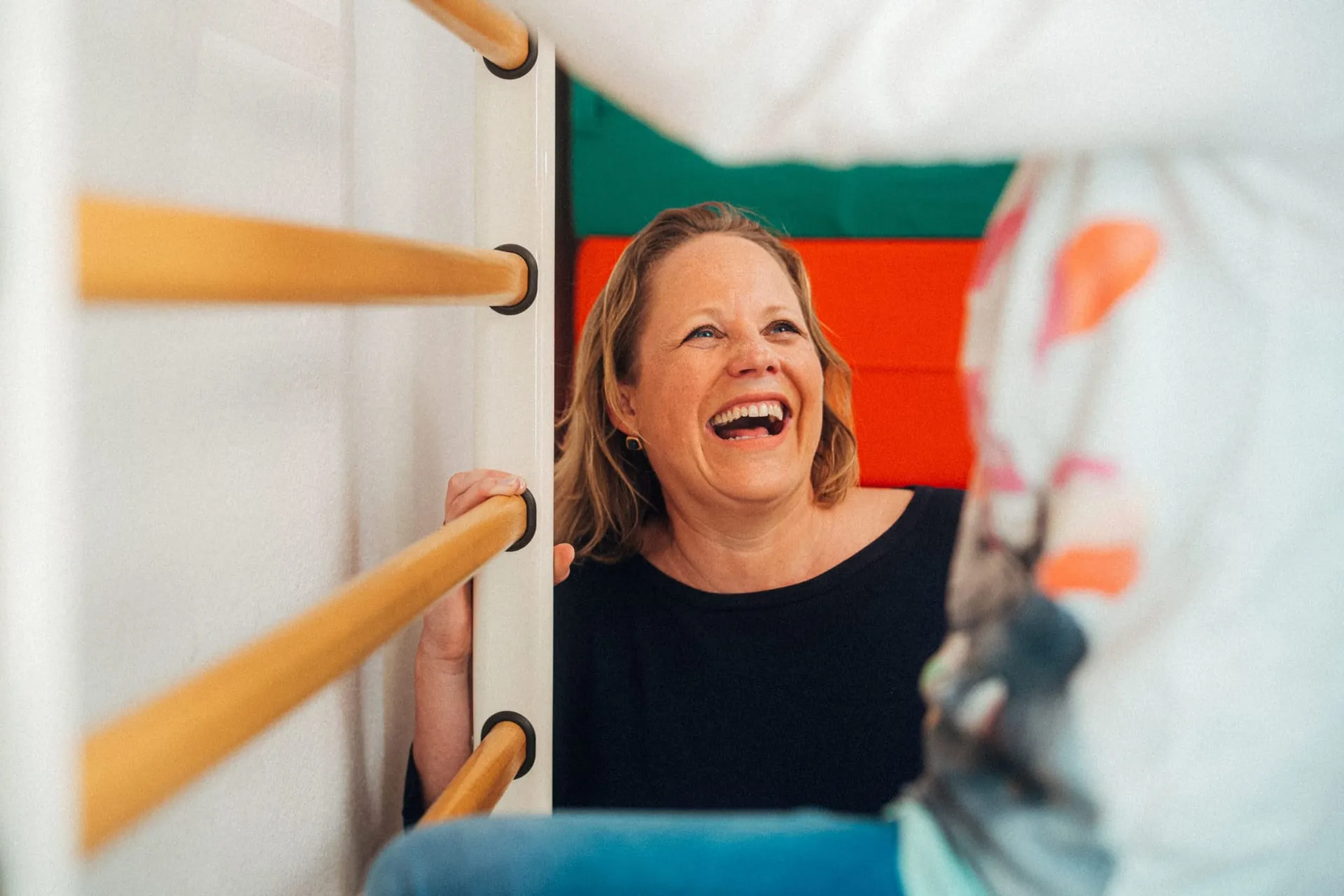 Ergotherapeutin Barbara Pfeiffer lacht an der Sprossenwand im Kinder-Therapieraum