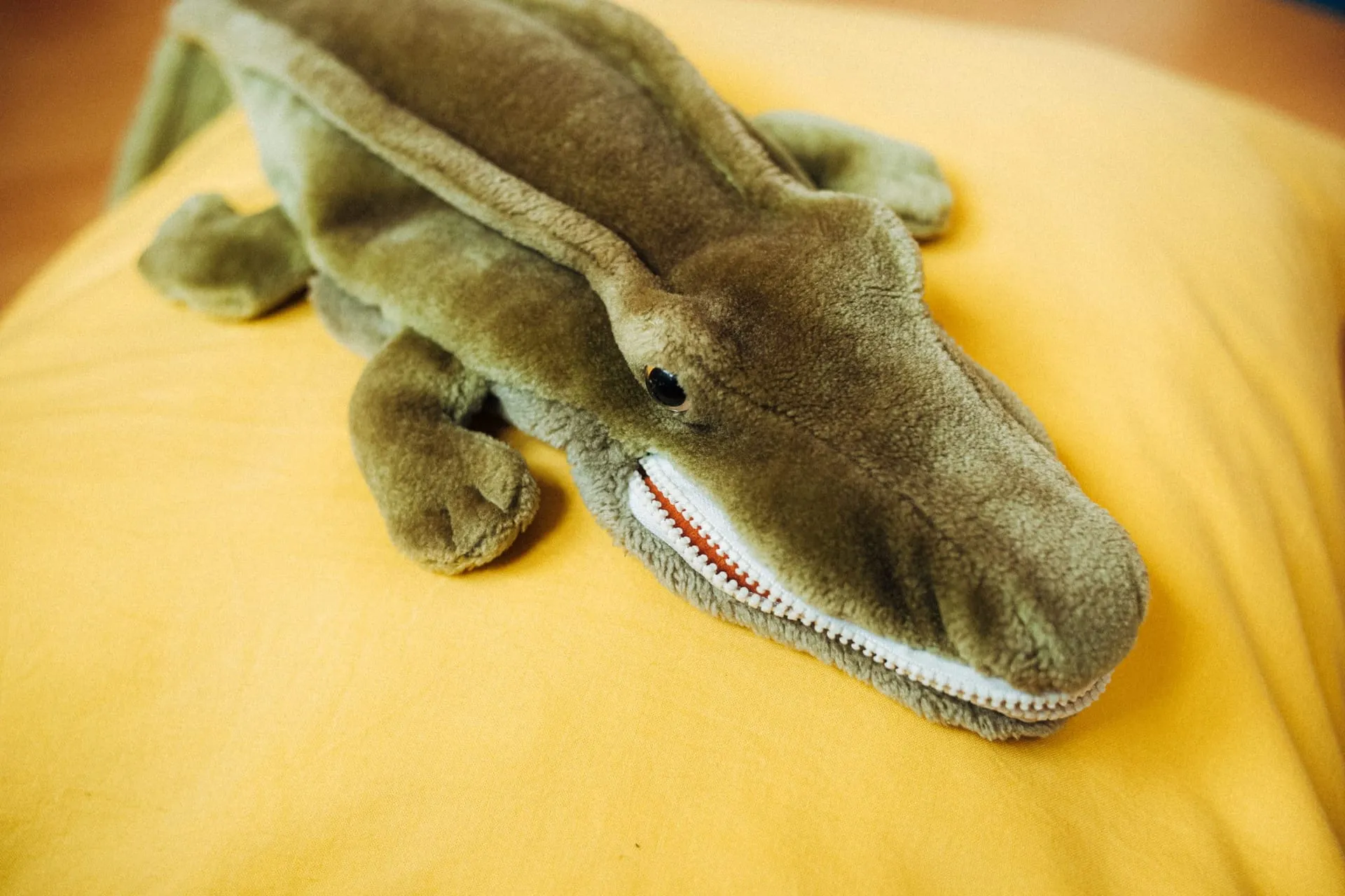 Plüsch-Krokodil als Therapiematerial auf einem gelben Kissen