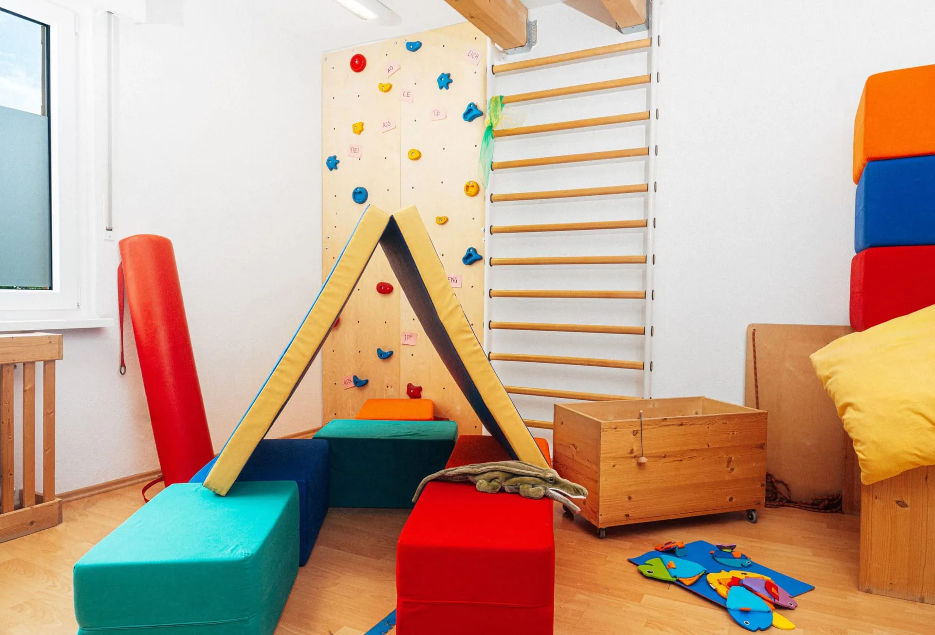 Therapieraum mit Sprossenwand, Kletterwand und bunten Schaumstoffelementen